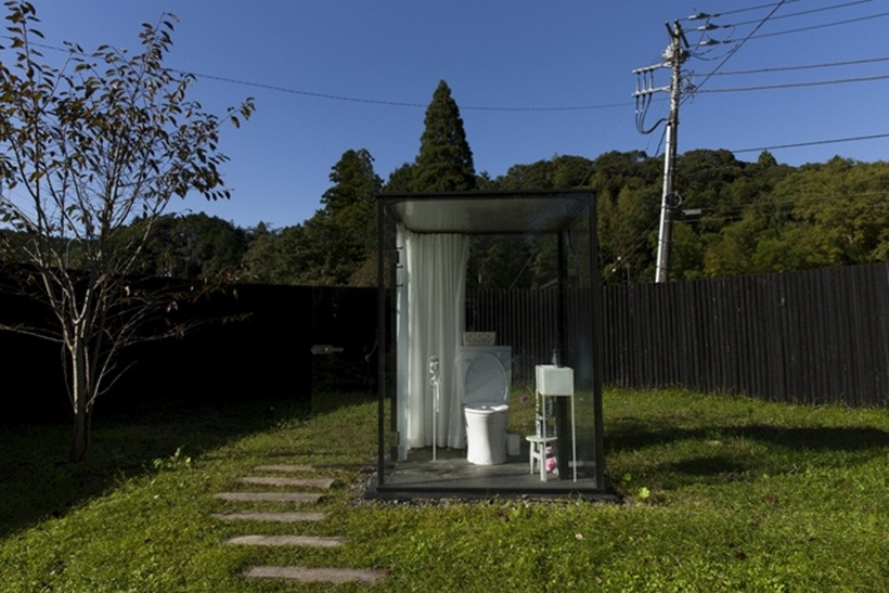 toilet cubicle with glass walls stands in a fenced off garden at Itabu railway station in the Chiba