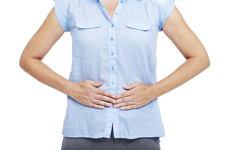 Cropped image of a woman pushing on her stomach with both hands - isolated on white