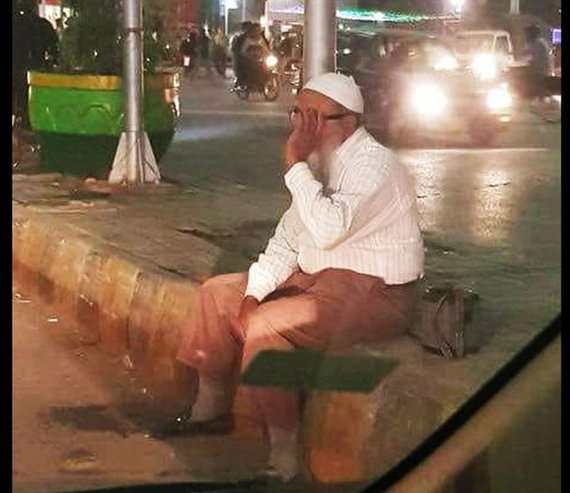 Well dressed man cleans cars at traffic signal in Pakistan